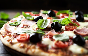 Pizza with ham, mozzarella cheese, cherry tomatoes, green and jalapeno pepper, black olives and fresh basil. Dark background. Close up.	