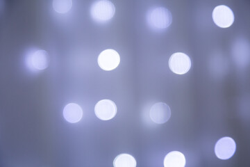 Luzes brancas acesas, desfocadas, em bokeh, com uma cortina de voal transparente por cima.