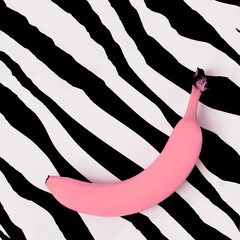 Minimal abstract composition with pink colored banana on black on white zebra texture. Flat lay background with copy space for text.