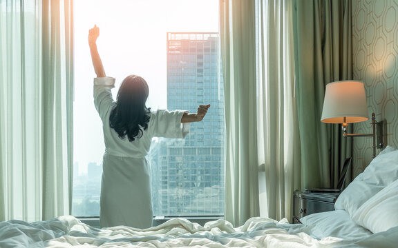 Work-Life balance, life quality, work and travel concept with businesswoman stretching in rest, relaxing, take it easy in modern hotel guest room or luxury home living room with notebook and city view