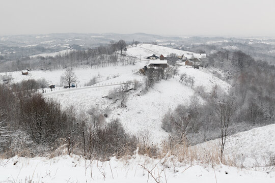 Farm on hill in winter, hilly village landscape during cold day with snow
