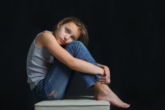 portrait of a sad preteen girl on black background