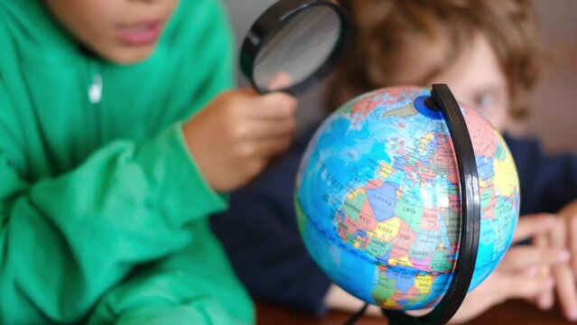 Little boys studying Earth planet on globe at table