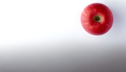 Artistic shot of a single, vibrant red apple on a white surface, located in the lower left corner, 