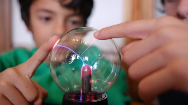 Little boys studying plasma ball with lightning at table