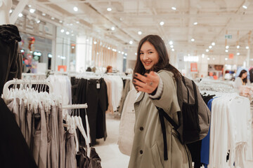 Korean teenage girl choosing and buying trendy clothes in a shopping mall. Retail and consumerism. Sale promotion and shopping concept. Part of a series - 772390868