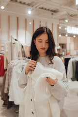 Korean teenage girl choosing and buying trendy clothes in a shopping mall. Retail and consumerism. Sale promotion and shopping concept. Part of a series - 772391285