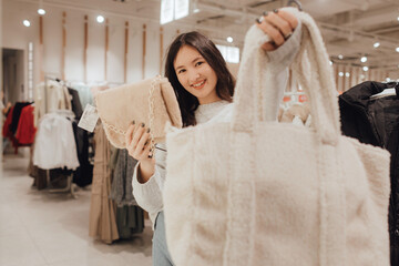 Korean teenage girl choosing and buying trendy clothes in a shopping mall. Retail and consumerism. Sale promotion and shopping concept. Part of a series - 772392042