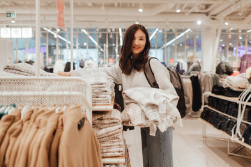 Korean teenage girl choosing and buying trendy clothes in a shopping mall. Retail and consumerism. Sale promotion and shopping concept. Part of a series - 772395414
