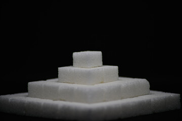 Eine weiße, gestufte Zuckerpyramide vor dunklem Hintergrund