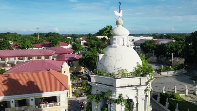 Drone footage of Vigan Cathedral's Spanish colonial bell tower with greenery on a sunny day