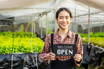 Portrait of young asian woman farmer holding open sign on hydroponics organic vegetable farm, Owner...