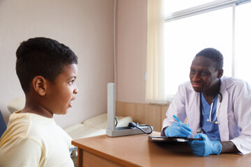 african american man pediatrician doctor talking to examining a boy from sickness in the office at...