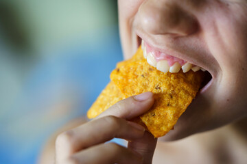 Crop unrecognizable teenage girl biting delicious Mexican tortilla chips