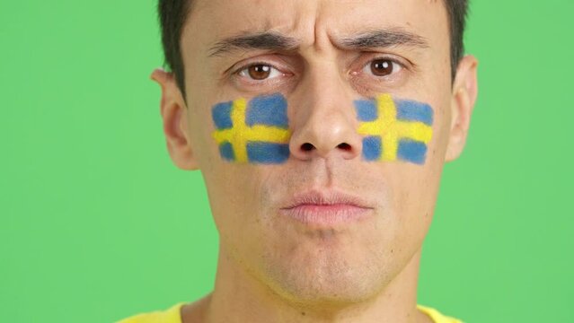 Serious man with a swedish flag painted on the face