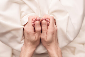 Baby feet of a newborn in dad's hands. On a white background.