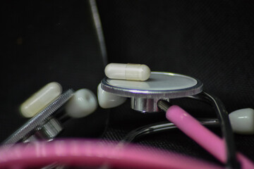 Eine Pille auf einem Stethoskop liegend sich spiegelnd in einem Spiegel auf dunklen Hintergrund 