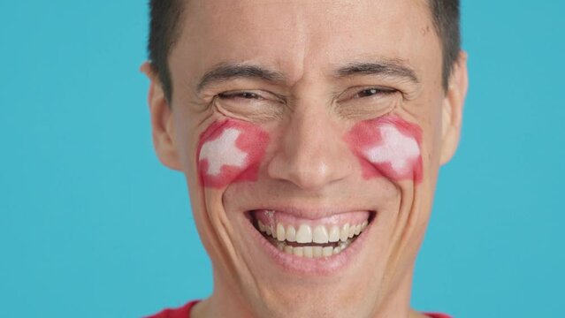 Man with a swiss flag painted on the face smiling