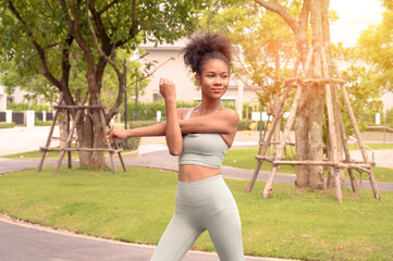 Portrait of fit young female stretching body in outdoor park. Beautiful African woman preparing, practicing, training. sport, lifestyle, summer mood concept.