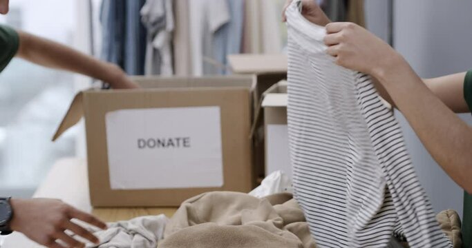 People, fold and clothes in boxes for donation, charity and volunteer with working in organisation. Hands, packing and sorting with generosity for corporate social responsibility and ngo foundation