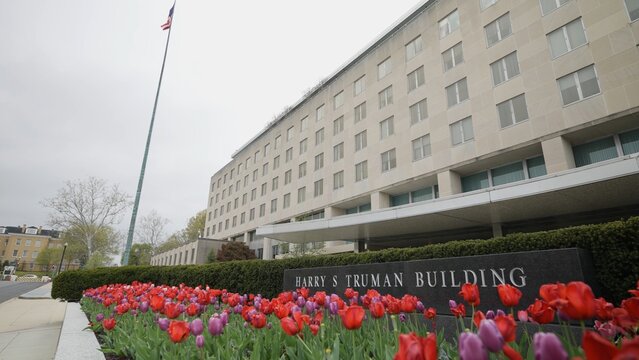 Front turning view of Harry S Truman Department of State building in Washington, DC on an overcast day with tulips in bloom.