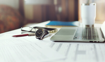 Close-up shot, wrist watch with laptop computer, business documents and mobile on table. check the...