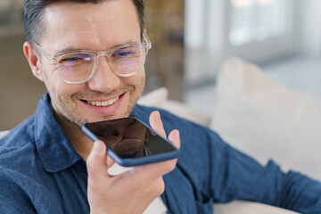 A cheerful man converses on his smartphone, his smile hinting at a pleasant dialogue, while clear eyeglasses frame his engaged expression. - obrazy, fototapety, plakaty
