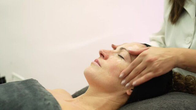 Beautician doing beauty massage on face of client in spa