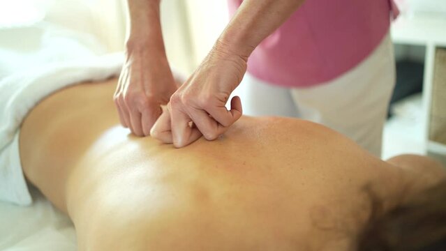 Crop osteopath massaging back with hands in salon