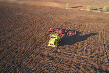 Pre-sowing tillage. Tractor with trailed combined machine on the field. Shooting from a drone.