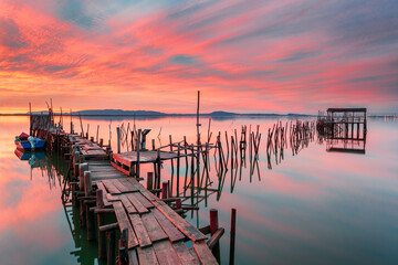 Amazing sunset on the palatial pier of Carrasqueira, Alentejo, Portugal. Wooden artisanal fishing port, with traditional boats on the river Sado. fineart color horizontal photography.