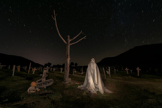 night view at the mythical Sad Hill cinematic cemetery with a dry tree and a ghost among the graves