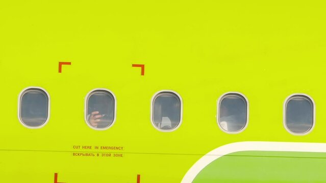 Windows of airplane outside. Exterior of plane in flight. View on portholes of aircraft. Airplane for travel. Green aeroplane with glass windows. Passenger aircraft, side view