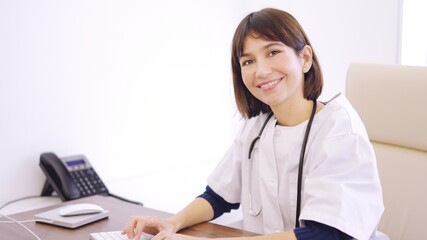 Female doctor using computer and smiling at camera