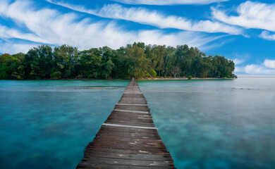Serene Coastal Scene with Long Wooden Jetty Extending into Turquoise Waters, Dramatic Sky Above