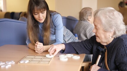 Senior woman playing board game with a woman