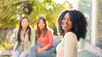 African woman smiling while chatting on the garden with friends