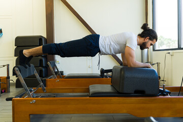 Man performing exercise on pilates reformer