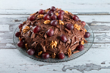 Cake with chocolate icing and grapes on a rustic background - 772470466