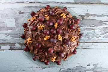 Cake with chocolate icing and grapes on a rustic background - 772470495