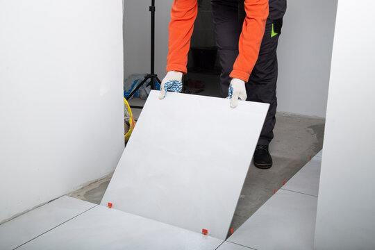 Installing ceramic tiles on the floor. A worker installs ceramic tiles at home.