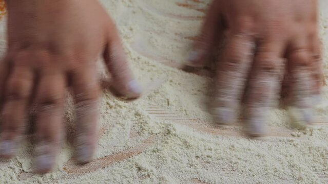 Female hands level flour on a wooden table, medium plan. Slowmotion