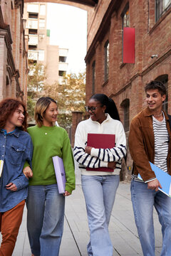 Internacional group of university students walking at school campus, talking and bonding while entering together to class. Vertical image with copy space.