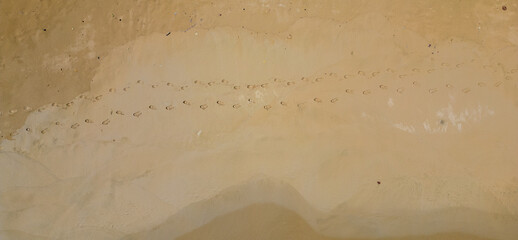 Footprints of people in the golden sand of a beach. Aerial view. Waves on the beach. Drone...