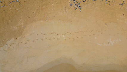 Footprints of people in the golden sand of a beach. Aerial view. Waves on the beach. Drone photography for travel agency. travel photography