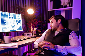 Fototapeta na wymiar Smart businessman leaning on chair with working desk, unfinished product service sales channel report, waiting for market data long time updated at purple neon dark light room at late night. Surmise.