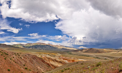 red and green mountains under fine large clouds