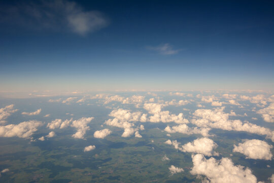 View from the sky above the clouds to the surface of the earth to the horizon on the background of the blue sky