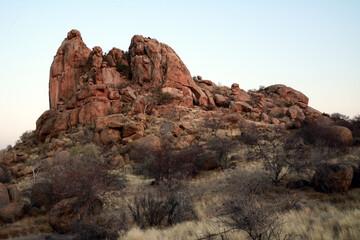 A rocky hill in a rocky arid terrain under a blue sky. Desert landscape and nature