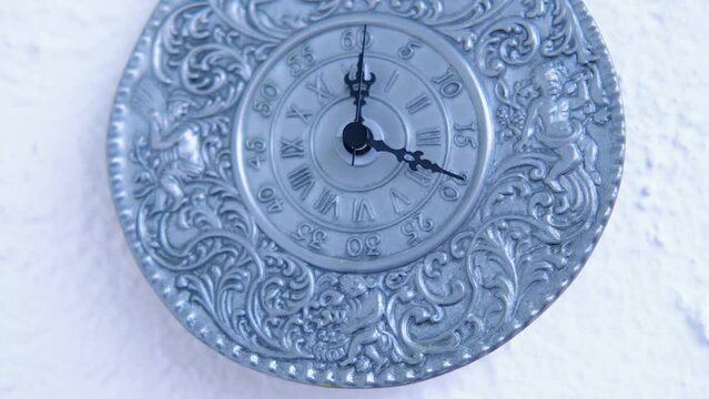 vintage silver clock of 19th century on white wall counts down the time, the hands move on dial, concept of road of life, time goes by, an irreversible flow from past, through present to future
